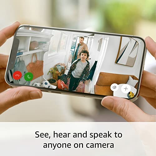 Hands holding smartphone showing a video call with a child and adult in a modern home.